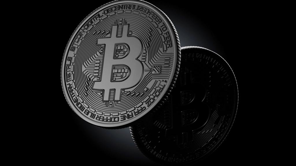 Two dark metal bitcoin coins on a black background