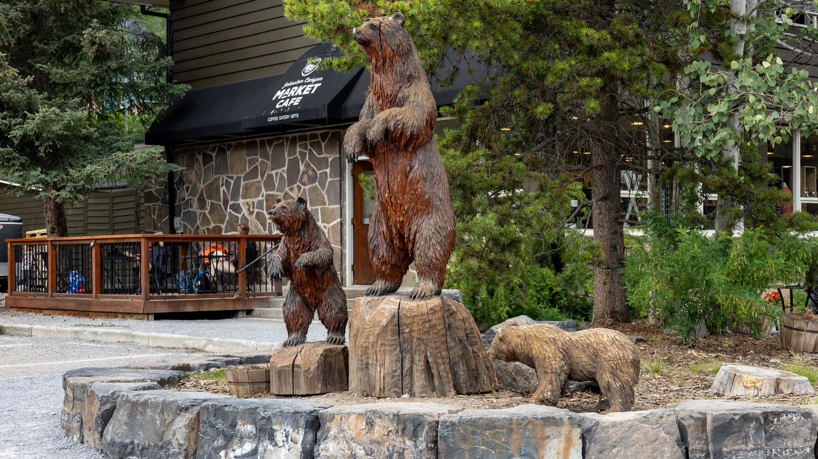 Three carved wooden bear statues, one standing tall, outside a building at Johnston Canyon in Banff National Park, Alberta.